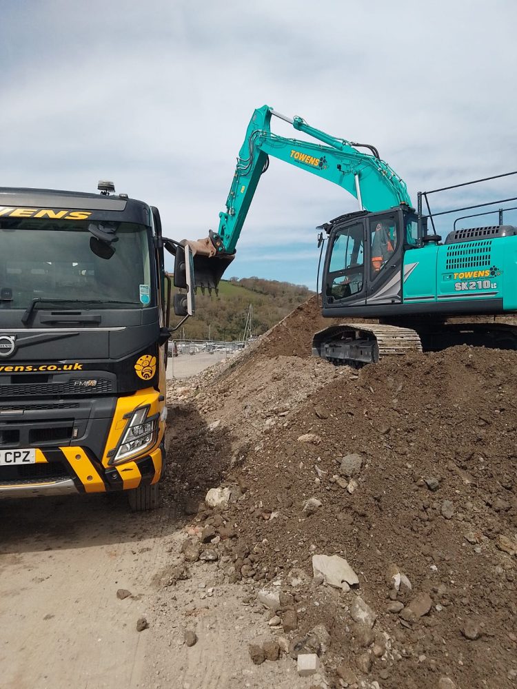 Towens excavator loading spoil into a Volvo FMX tipper at Noss on Dart Marina during an earthworks and site clearance project.