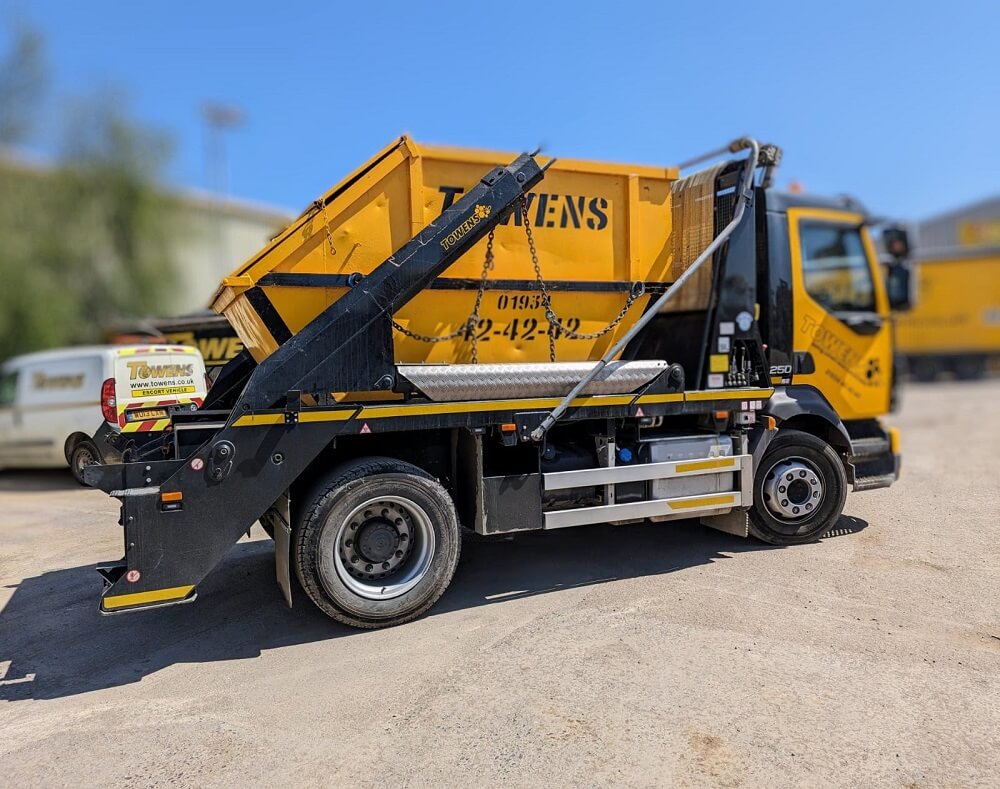 Towens skip lorry used for waste management services, featuring a yellow skip and Towens branding.