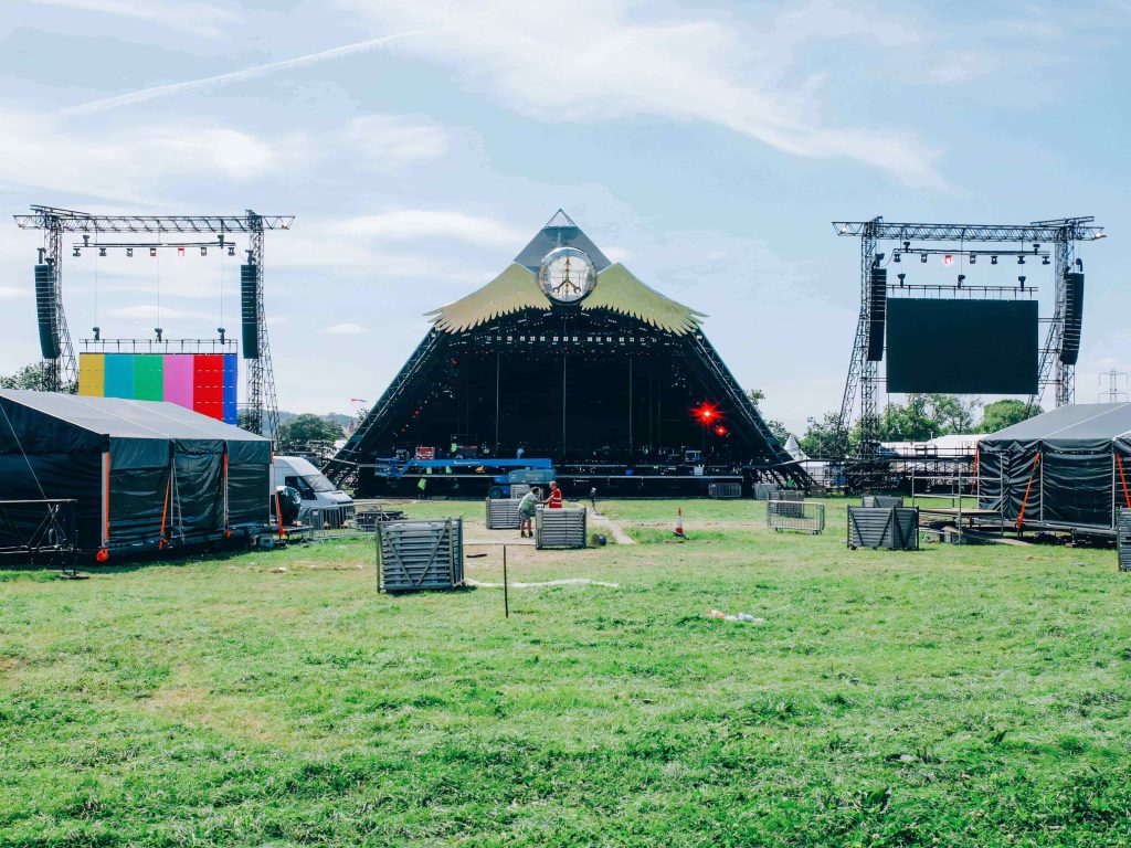 Pyramid Stage setup at Glastonbury Festival, showing lighting rigs, sound systems, and festival infrastructure being prepared.
